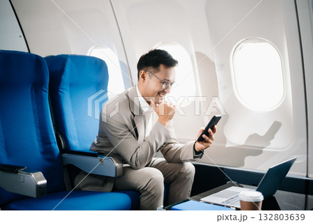 Young Asian executive excels in first class, multitasking with digital tablet, laptop and smartphone. Travel in style, Young Asian executive excels in first class, multitasking with digital tablet, laptop and smartphone. Travel in style, 132803639