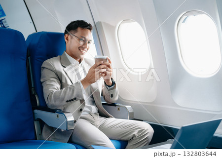 Young Asian executive excels in first class, multitasking with digital tablet, laptop and smartphone. Travel in style, Young Asian executive excels in first class, multitasking with digital tablet, laptop and smartphone. Travel in style, 132803644