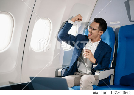 Young Asian executive excels in first class, multitasking with digital tablet, laptop and smartphone. Travel in style, 132803660