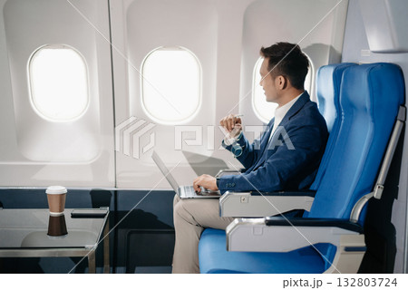 Young Asian executive excels in first class, multitasking with digital tablet, laptop and smartphone. Travel in style, Young Asian executive excels in first class, multitasking with digital tablet, laptop and smartphone. Travel in style, 132803724