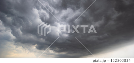 A dramatic sky filled with swirling dark clouds signals an impending windstorm, capturing the intense atmosphere of shifting weather and emphasizing the power of nature and environmental change. 132803834