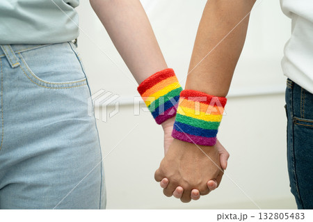 Asian LGBT couple woman holding hand wearing rainbow wristband. 132805483