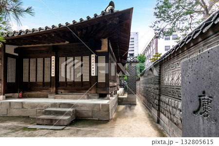 Corner view of Korean traditional wooden buildings and patterned stone walls inside Unhyeongung Palace, highlighting the harmony of Joseon-era architecture and urban surroundings 132805615