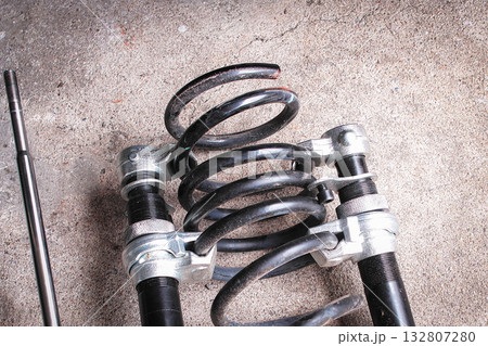 Car shock spring being removed with spring removal tool for replacement in auto repair shop Car shock spring being removed with spring removal tool for replacement in auto repair shop 132807280