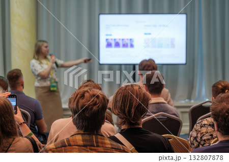 Speaker presents to a conference audience with a large screen display in a bright meeting room Speaker presents to a conference audience with a large screen display in a bright meeting room 132807878