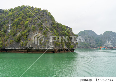 A captivating view of the emerald waters surrounding limestone karsts in Ha Long Bay, Vietnam, under an overcast sky. A captivating view of the emerald waters surrounding limestone karsts in Ha Long Bay, Vietnam, under an overcast sky. 132808733