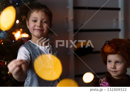 Two children are holding burning sparklers with looks of awe and joy on their faces Two children are holding burning sparklers with looks of awe and joy on their faces 132809322