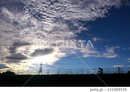 陽の落ちかける遊歩道を走り抜ける一台の自転車のシルエット 132809336