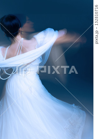 Dancer back in soft blue light, pearls tracing fluid choreography lines. 132810716