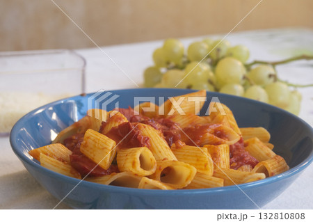 rigatoni pasta with fresh cherry tomato sauce in blue bowl on table 132810808
