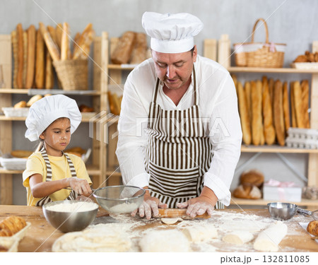 Little daughter and father make dough together in bakery kitchen 132811085