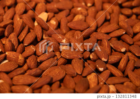 Delicious roasted almonds with spices are sold in large quantities at a vegetable market. Close-up. Almond background. Delicious roasted almonds with spices are sold in large quantities at a vegetable market. Close-up. Almond background. 132811348