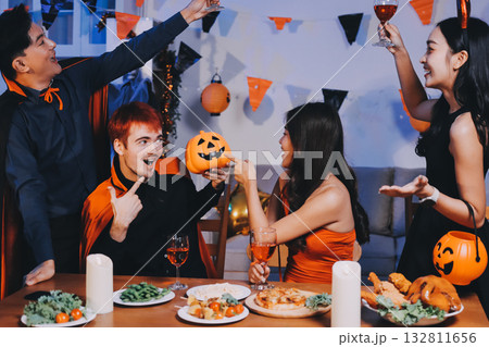 Joyful office Halloween party with coworkers in costumes, celebrating with drinks and laughter, fostering teamwork and festive spirit 132811656