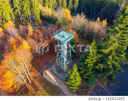 Discover the beauty of Slovanka Lookout Tower located in the Jizera Mountains. Surrounded by vibrant autumn foliage, this historic iron tower offers a stunning view of the fall landscape. 132812201