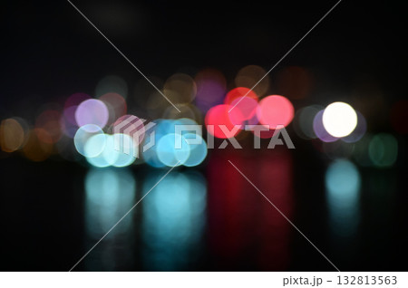 Bokeh effect of the light of skyscrapers from the seaside at night. Colorful and bright lights at night in the city. Nature and city scene. Bokeh effect of the light of skyscrapers from the seaside at night. Colorful and bright lights at night in the city. Nature and city scene. 132813563