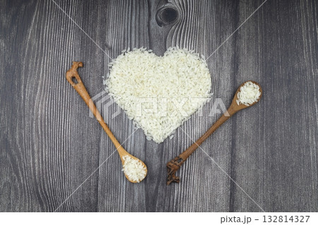 Heart-shaped rice on dark background. Love and valentines day concept. Raw long white rice in shape of heart. Traditional Asian food. 132814327