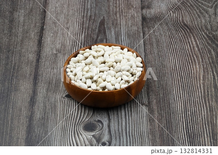 white kidney bean in wooden bowl isolated on wooden background. Top view. Flat lay white kidney bean in wooden bowl isolated on wooden background. Top view. Flat lay 132814331
