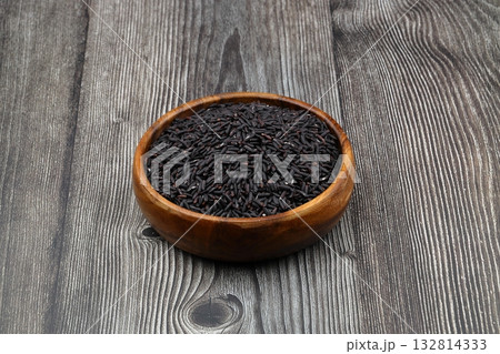 pile of black rice in a wooden bowl on a wooden table close-up pile of black rice in a wooden bowl on a wooden table close-up 132814333
