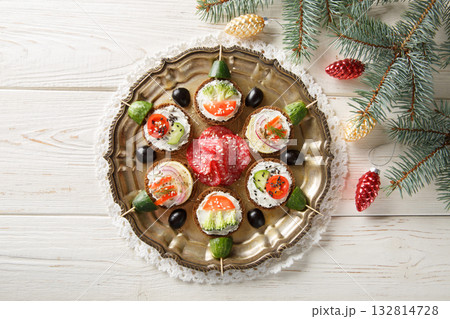 Christmas canapes decoration idea with cream cheese and vegetables close-up in a plate. Horizontal top view Christmas canapes decoration idea with cream cheese and vegetables close-up in a plate. Horizontal top view 132814728