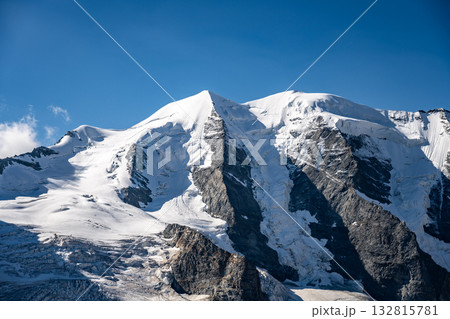 Piz Palu towers in the Swiss Alps, showcasing its rugged glaciers and stunning peaks against a clear blue sky. This breathtaking landscape offers a glimpse into alpine beauty and adventure. 132815781