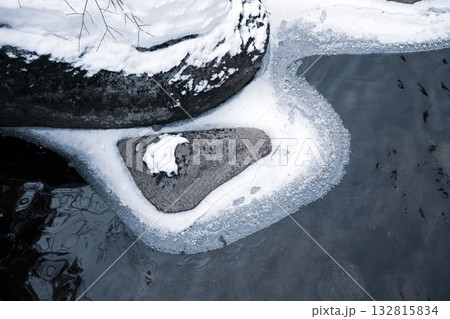 In winter, the Jizerka River flows slow and cold, surrounded by snow-covered rocks and ice. This serene scene captures the beauty of the Czech wilderness in the chilly season. 132815834