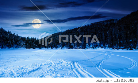 winter landscape with snow covered ground at night. mountains with frozen lake among spruce forest in full moon light. scenic view of winter wonderland. background for investment or abstract concepts winter landscape with snow covered ground at night. mountains with frozen lake among spruce forest in full moon light. scenic view of winter wonderland. background for investment or abstract concepts 132816392