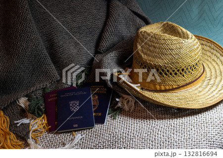 Several passports and stylish straw hat resting on a cozy knit blanket. Copy space 132816694