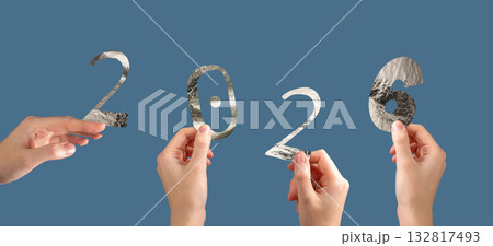Hand holding silver metallic 2026 number in festive New Year celebration. Shiny textured foil Hand holding silver metallic 2026 number in festive New Year celebration. Shiny textured foil 132817493