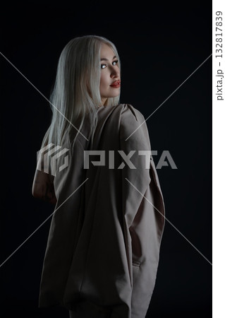 Model with long silver hair posing against a dark background in soft light Model with long silver hair posing against a dark background in soft light 132817839