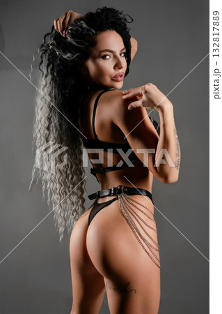 Sensual woman in stylish lingerie poses confidently against gray backdrop 132817889