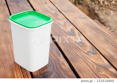 white container with a green lid on a wooden surface, angled view white container with a green lid on a wooden surface, angled view 132818868