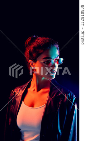 Woman in red and blue light wearing slim sunglasses and leather jacket Woman in red and blue light wearing slim sunglasses and leather jacket 132818938
