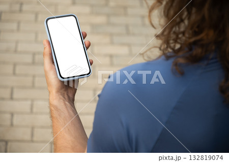 Athlete or sporty fit man holding mobile phone with empty white blank screen at modern city. Mock up. Check apps, focused on device, chatting or browsing internet. Outdoors. Athlete or sporty fit man holding mobile phone with empty white blank screen at modern city. Mock up. Check apps, focused on device, chatting or browsing internet. Outdoors. 132819074