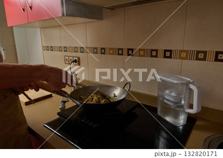 Father Cooking Stir-Fry In Warm Kitchen While Child Helps Prepare Dinner Father Cooking Stir-Fry In Warm Kitchen While Child Helps Prepare Dinner 132820171