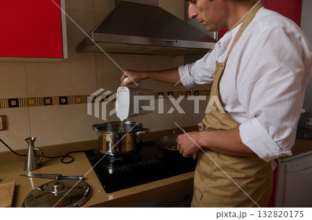 Father Cooking Soup In Kitchen While Child Helps With Dinner Preparation 132820175