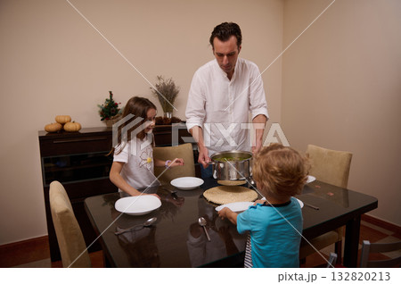 Father Cooks Soup For His Kids At Dinner Table, A Warm Family Moment 132820213