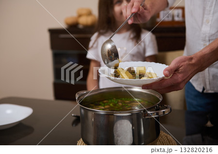 Father Serves Soup to Family as Daughter Helps in Cozy Home Kitchen Father Serves Soup to Family as Daughter Helps in Cozy Home Kitchen 132820216