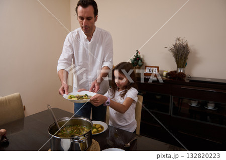 Father Serves Soup To Daughter During Family Dinner At Home Father Serves Soup To Daughter During Family Dinner At Home 132820223