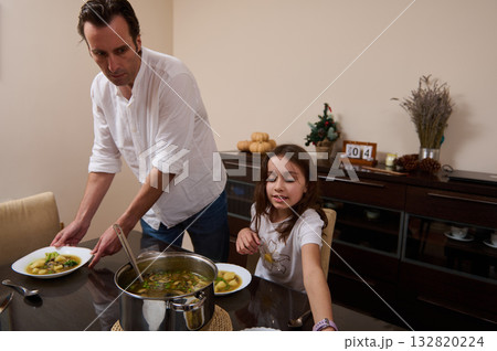 Father And Daughter Cooking Soup For Dinner In Modern Kitchen, Cozy Family Moment Father And Daughter Cooking Soup For Dinner In Modern Kitchen, Cozy Family Moment 132820224