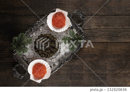 Black and red caviar on a silver-plated tray and on ice. Natural delicacy. Branch of spruce and ice on a tray. Natural omega. Flat lay. Top view. Copy space. Black and red caviar on a silver-plated tray and on ice. Natural delicacy. Branch of spruce and ice on a tray. Natural omega. Flat lay. Top view. Copy space. 132820636
