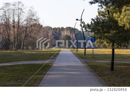 Empty bike and pedestrian path through quiet parkland toward forest 132820958