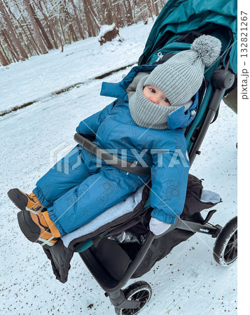 Baby in winter snowsuit in stroller on snowy path Baby in winter snowsuit in stroller on snowy path 132821267