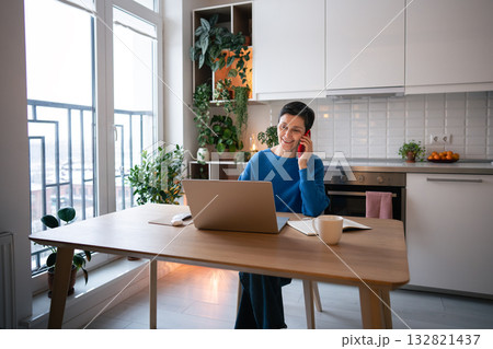 Mature woman smiling while on business call, work on laptop at home. Remote work, self employed job Mature woman smiling while on business call, work on laptop at home. Remote work, self employed job 132821437