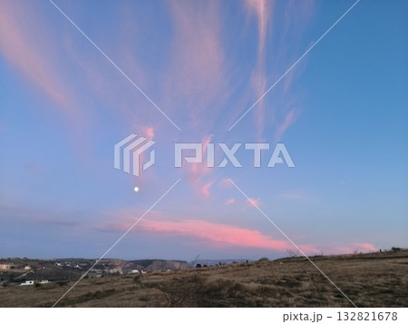 A full moon in a colorful twilight sky with pink clouds over a rural hillside. Scenic countryside landscape at dusk A full moon in a colorful twilight sky with pink clouds over a rural hillside. Scenic countryside landscape at dusk 132821678