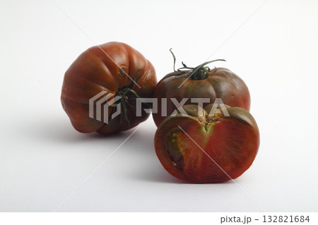 Black organic tomatoes with cuttings. Round black tomatoes. On a white background, isolated. Black organic tomatoes with cuttings. Round black tomatoes. On a white background, isolated. 132821684