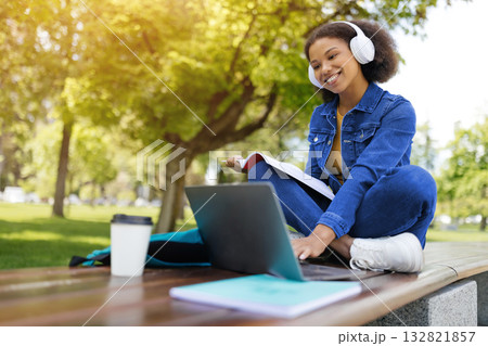 Happy black female student study outdoors with laptop and workbooks 132821857