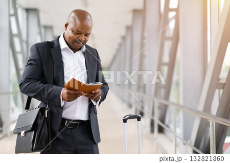 Focused African American businessman in suit reading passport and ticket at airport 132821860
