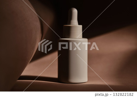 A bottle of face serum on a brown chocolate background. A bottle of face serum on a brown chocolate background. 132822182