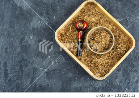 Smoking pipe with tobacco on a table. 132822512