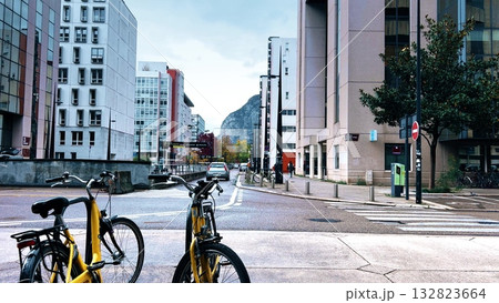 Modern street scene with bicycles and cars on Avenue Doyen Louis Weil in Grenoble, France, surrounded by contemporary architecture and autumn colors with mountains in background Modern street scene with bicycles and cars on Avenue Doyen Louis Weil in Grenoble, France, surrounded by contemporary architecture and autumn colors with mountains in background 132823664